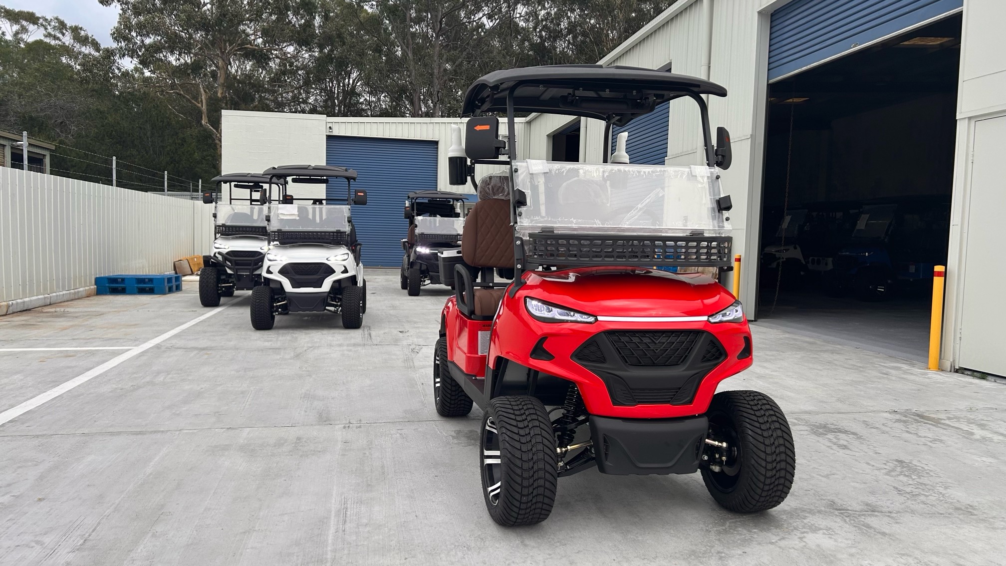 Red JSH0701 two-seat golf cart at a vehicle facility